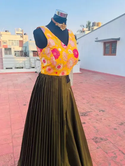 The vibrant yellow blouse contrasts beautifully with the earthy green skirt.