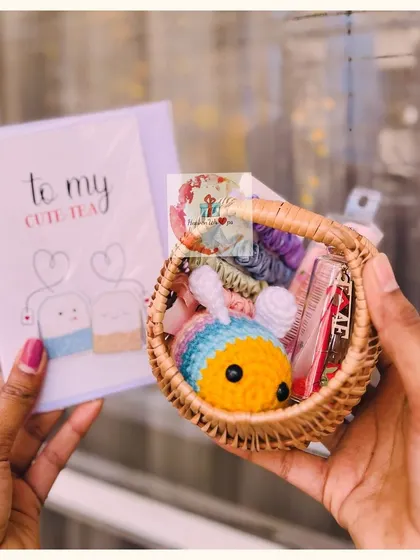 A tiny woven basket holding a crocheted bee toy and other small accessories, paired with a "To my cute-tea" card for a playful Valentine's gift.