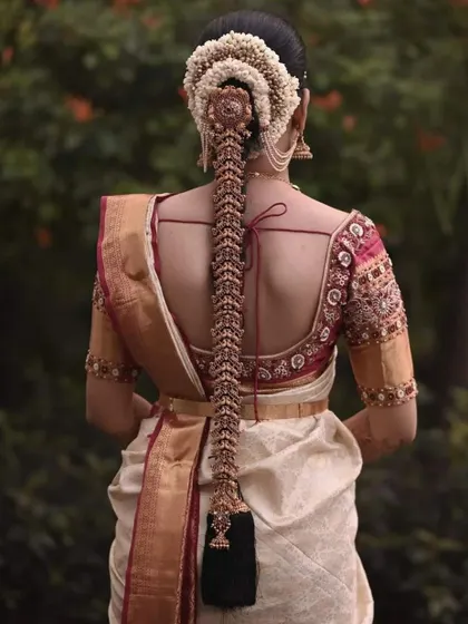 The complete traditional look from the back. Her custom-embroidered blouse is designed to perfectly complement her elaborate bridal hairstyle and off-white silk saree.