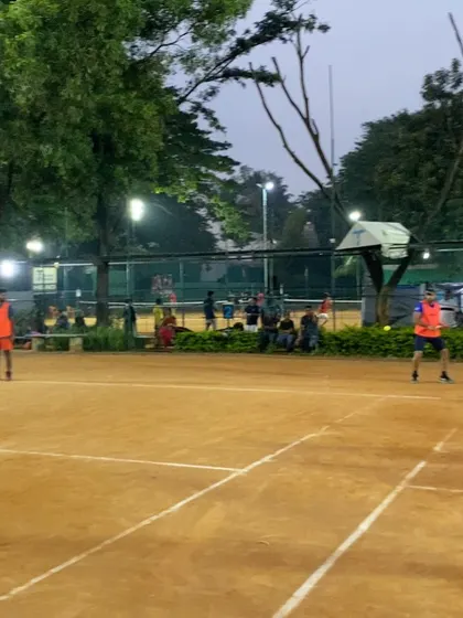 Spectators watch a doubles match from the sidelines. We have benches and seating areas, making it comfortable for friends and family to watch and support.