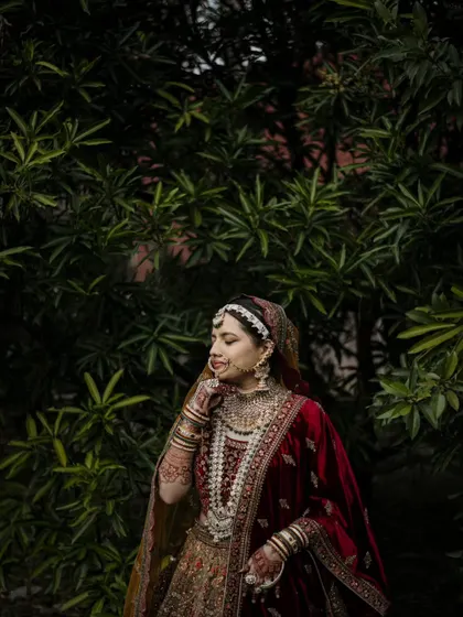 A candid-style portrait of a Muslim bride in a lush garden setting. Her natural expression and the soft light create a beautiful, serene image.