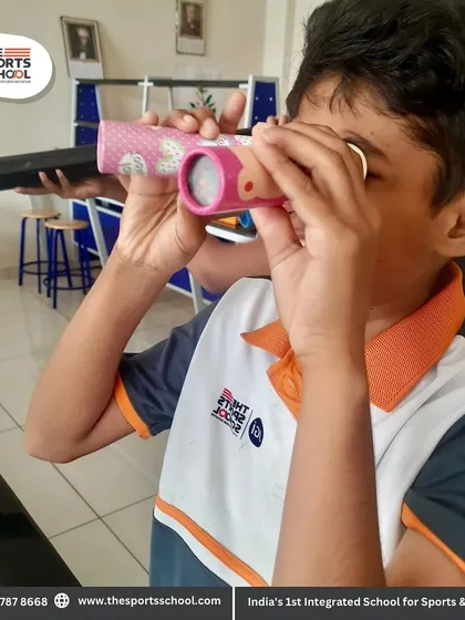 Another student engaged in the science lab, exploring the world through a handmade optical instrument.