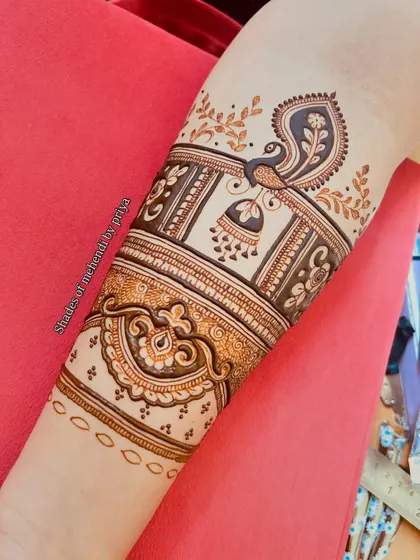 A close-up of the upper arm portion of the design, highlighting the peacock and jhumka (earring) motif.