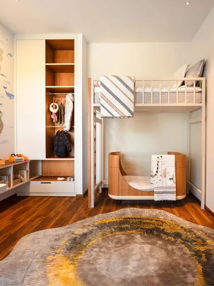 A thoughtfully designed children's room with a bunk bed and integrated storage. The space is both playful and practical, featuring a world map mural and a custom rug to spark imagination.