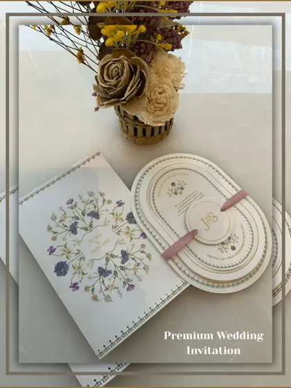 A premium wedding invitation set featuring a unique oval-shaped multi-layered card, held together by a personalized band. This modern design is perfect for contemporary couples.