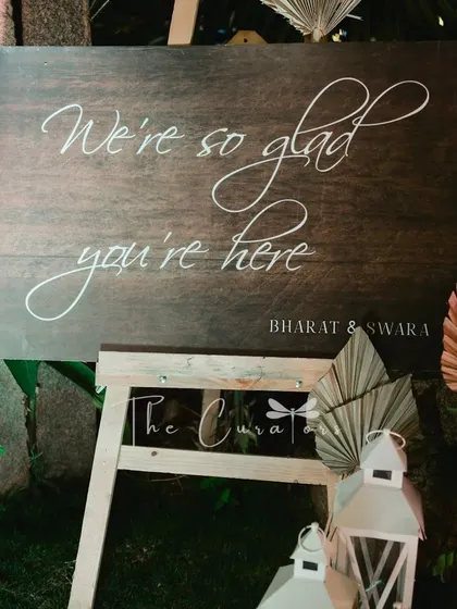This detail shot of the welcome sign shows the elegant calligraphy and the thoughtful arrangement of flowers and lanterns that greet guests.