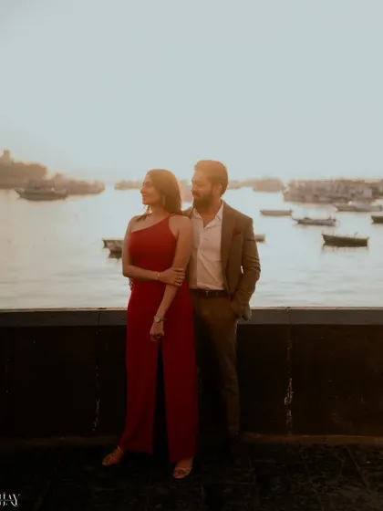 A silhouette-style shot of the couple against the bright morning sun over the Mumbai harbor.