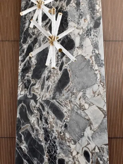 A stunning floor-to-ceiling accent wall that demonstrates our expertise in combining materials. A central slab of dramatic black and grey stone is flanked by warm, vertically fluted wood panels, creating a powerful focal point in this luxury space.