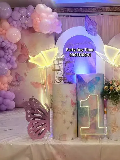 A beautiful butterfly theme for a first birthday. This setup features pastel balloon garlands, light-up butterfly props, and a milestone board showing the baby's first year.