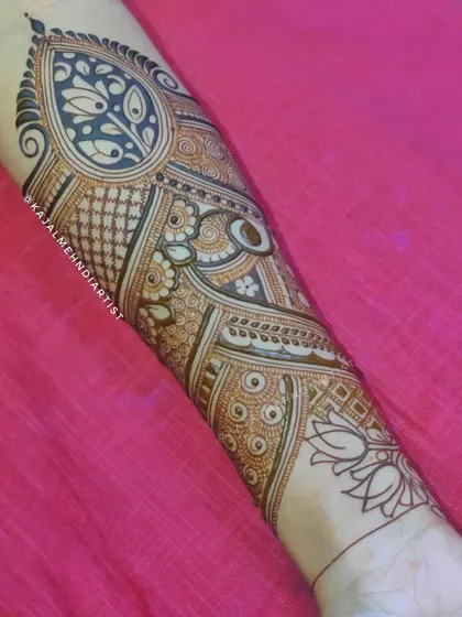 A close up of a detailed bridal armband. This design features a large paisley motif filled with intricate patterns, with delicate lotus flowers drawn near the wrist.