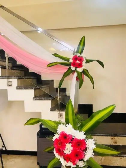 Staircase railing decoration using drapes and floral bouquets. This adds a touch of elegance to the home's interior during a celebration.