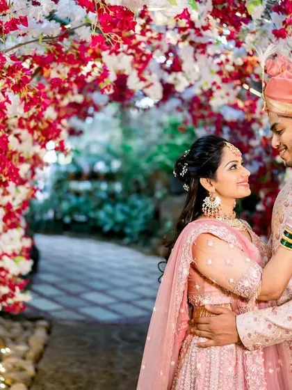 An intimate embrace within a tunnel of red and white flowers. The flowers create a beautiful natural frame, drawing all the attention to the couple's loving gaze.