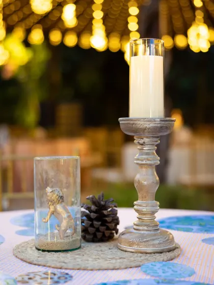 A beautiful tablescape detail from the Lion King party, featuring a candle, a pinecone, and a glass vase with a golden lion figure inside, all set on a woven jute placemat.