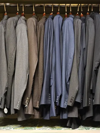 A collection of suits and blazers hung with care. Proper spacing and uniform hangers protect the garments and make it easy to select the right one for any formal occasion.