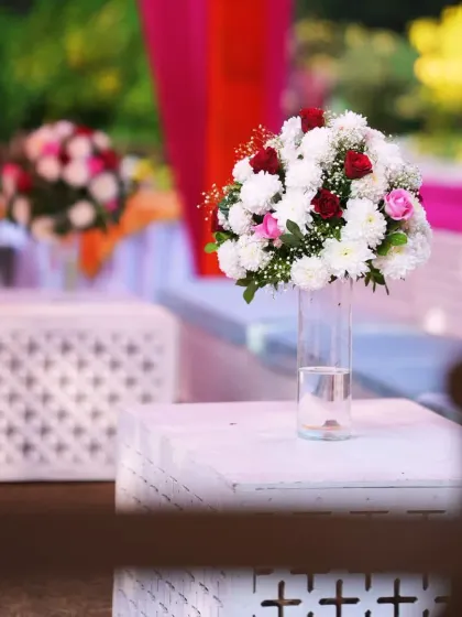 A close-up of a floral centerpiece on a modern white table, part of the elegant decor for a daytime Mehendi event.