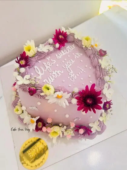 Love, flowers, and frosting. This heart-shaped cake with a sweet message is adorned with a wreath of fresh, colorful flowers.