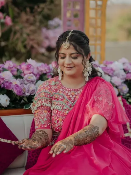 A beautiful bride looking at her mehandi. The intricate design and her elegant attire create a picture of grace.