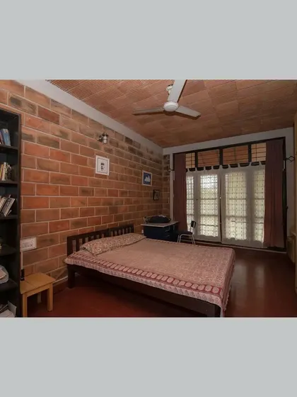 A bedroom with a built-in bookshelf, combining storage and study space within a calm, earthy environment.