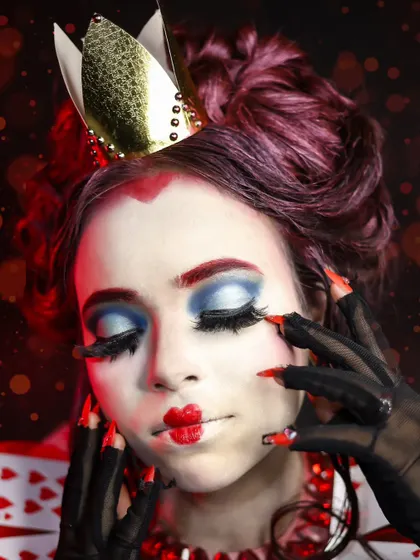 A close-up on the Queen of Hearts' iconic makeup, with the heart-shaped lips and dramatic blue eyeshadow.