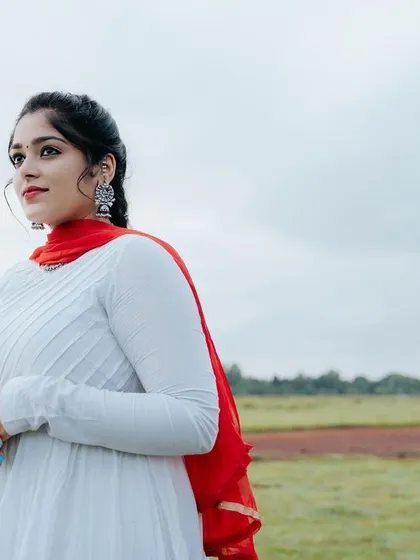 A beautifully composed shot with the bride in focus and the groom in the background, set against a wide-open field. This creates a sense of story and anticipation.