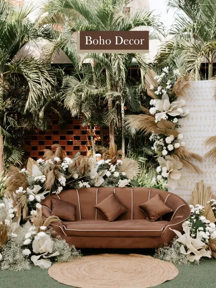 A closer look at a Boho decor setup, featuring a stylish brown sofa against a backdrop of pampas grass and white florals for the perfect photo opportunity.