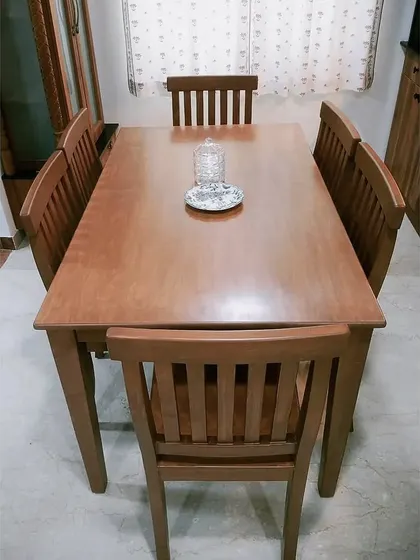 A top-down view of the six-seater dining table, showcasing the beautiful wood grain and the simple, functional design of the chairs.