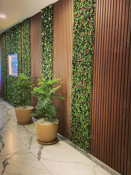 We designed this hallway by integrating vertical strips of artificial greenery with dark wood louvered panels. This combination of textures adds depth and a modern, natural feel to the commercial space.