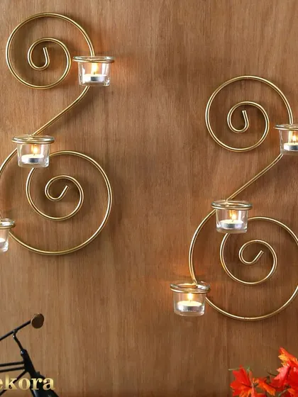 A pair of golden metal wall sconces for T-light candles, designed in a spiral shape. These are an elegant way to add ambient lighting to a hallway or a quiet corner in an office.