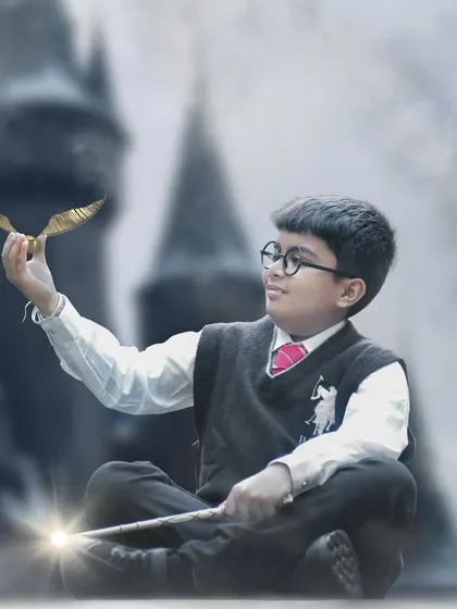 In this enchanting Harry Potter portrait, the young boy sits cross-legged, holding a glowing wand and admiring the Golden Snitch.