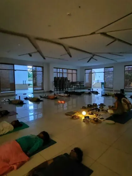 A beautiful, atmospheric shot of a healing workshop in the evening, with participants resting in Savasana surrounded by candlelight.