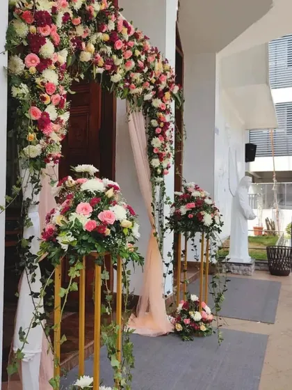 An elegant floral arch at the entrance of a church for a Christian wedding. The arrangement of pink and white roses with cascading greenery adds a touch of romance and beauty to the venue.