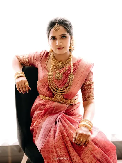 A stunning bridal portrait, showcasing the intricate gold jewelry and the rich color of her silk saree.