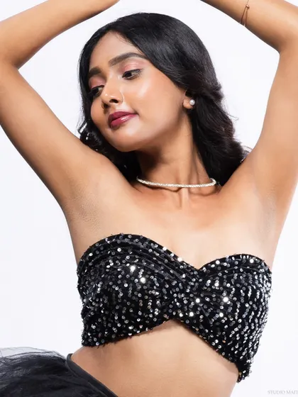 A graceful pose in a sequined top, with the model's arms raised.