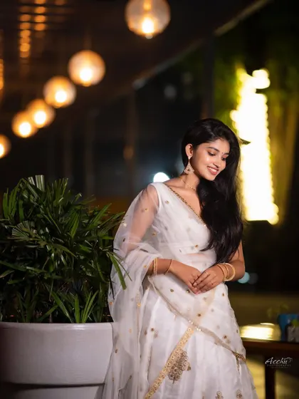 A candid and joyful moment captured under the festive lights. The natural smile and relaxed pose make this a perfect shot for a sangeet or reception event.