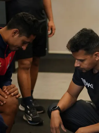 A one-on-one moment with a player, assessing his knee and discussing his physical state. Individual care is a cornerstone of my coaching.