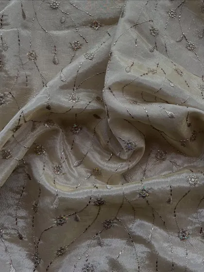 Our embroidered tissue fabric has a subtle metallic sheen, enhanced with delicate floral embroidery. It's a great choice for sarees and lehengas that require a bit of sparkle.