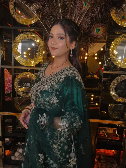 A confident and poised portrait. The model's makeup is subtle yet effective, enhancing her natural beauty and complementing the elegant green and gold attire.