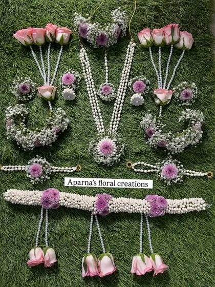 Here is a full baby shower jewellery set, laid out to show every detail. It includes a long necklace, choker, maang tikka, earrings, haath phool, and a kamarband (waistband), all made from fresh pink roses, purple flowers, and fragrant jasmine buds.