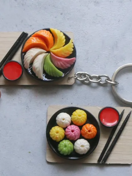A set of two momo keychains, one with steamed momos and the other with colorful pan-fried momos.