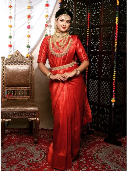 This bride looks absolutely stunning in a red saree and a full gold-plated bridal set. The layered necklaces create a look of pure opulence.