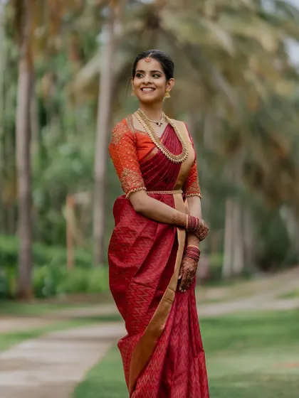 A smile that lights up the day. This candid bridal portrait captures the bride's infectious happiness and natural beauty in her stunning red saree.