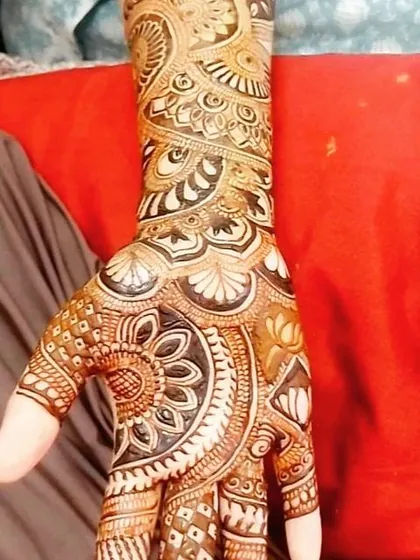 A close-up of a palm filled with traditional Indian mehendi elements, including mandalas, lotuses, and detailed finger designs.
