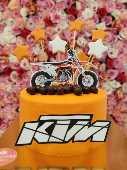 A KTM bike-themed cake for a motorcycle lover. The orange cake matches the brand's colors, and it's topped with a bike cutout and stars.