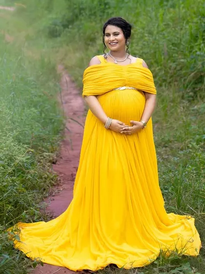 A beautiful solo portrait of the mom-to-be in a lush green pathway near the beach, the yellow gown providing a stunning contrast.