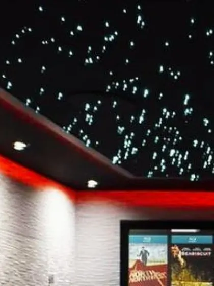 This home theater features a stunning fiber optic star ceiling and custom red ambient lighting to create a classic cinema feel. The textured acoustic wall panels not only enhance the look but also optimize the room's sound quality.