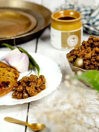 A deconstructed serving of the pickle with a piece of paratha on a white plate. This bright and airy shot offers a clean, modern take on presenting a traditional food item.