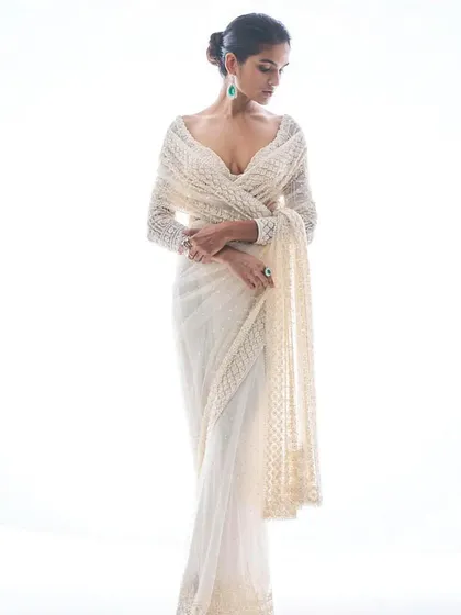 An elegant off-white saree with a full-sleeve embellished blouse. This look is a masterclass in understated glamour, perfect for a sophisticated engagement or reception.