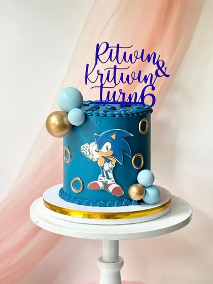 A Sonic the Hedgehog cake for a 6th birthday. The deep blue buttercream is decorated with golden rings and a printed image of Sonic, perfect for a video game fan.