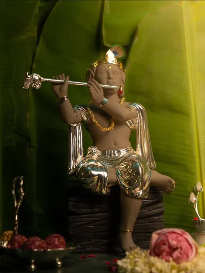 A serene Krishna idol, depicted playing his flute against a backdrop of banana leaves. This composition evokes a sense of divine calm and is perfect for celebrating Janmashtami or Chatti.