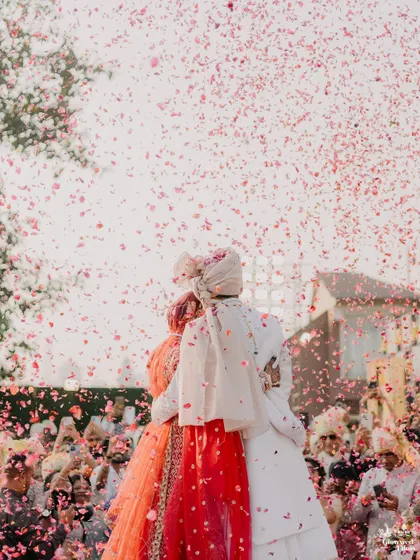 An artistic shot from behind the couple as they are showered with petals, creating a beautiful and immersive photograph of their special moment.